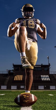 a football player standing on top of a football field with his foot on the ball