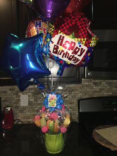 a bunch of balloons that are sitting in a vase on a counter top with the words happy birthday written on it