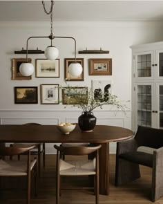 a dining room table with chairs and pictures on the wall