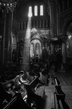 a person sitting on a bench in a church with sunlight streaming through the windows and lighting up the pews