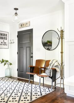 a living room with a black door and white walls, two chairs in front of the door