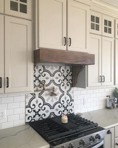 a stove top oven sitting inside of a kitchen next to white cabinets and counter tops