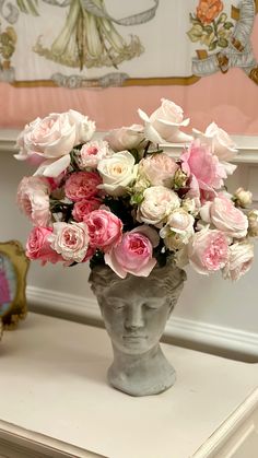 a vase filled with lots of pink and white flowers on top of a table next to a mirror