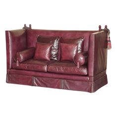 a red leather couch with three pillows on it's back and two side ends