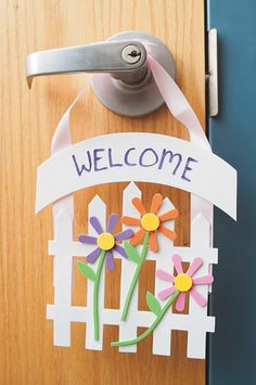 a door handle with flowers on it and the word welcome hanging from it's side