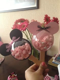 a person is holding up some candy in front of minnie mouse ears and pink flowers