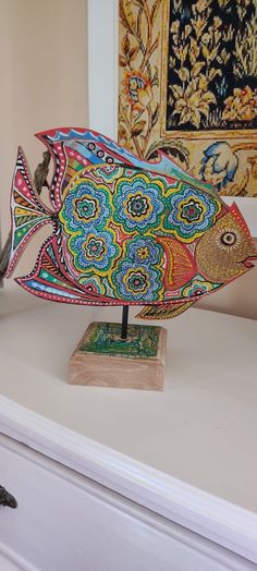 a colorful fish sculpture sitting on top of a white dresser