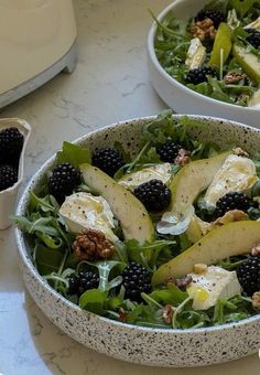 two bowls filled with salad and fruit on top of a table