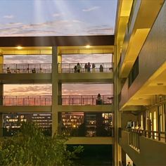 people are standing on the balconies of a high rise building at sunset or dawn