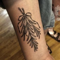 a woman's arm with an olive branch tattoo on it