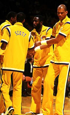 three men in yellow uniforms standing on a basketball court and shaking hands with each other