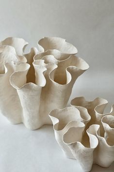 several white vases sitting next to each other on top of a table with no one around them