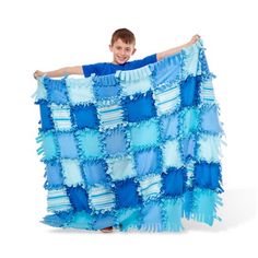 a young boy holding up a blue and white blanket with ruffles on it