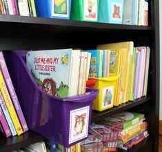 a book shelf filled with lots of children's books and plastic bins on top of it