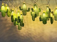 green glass cactus lights hanging from a metal barbwire with branches in the background