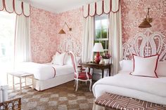 two beds in a room with pink and white wallpaper