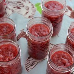 four jars filled with raspberry jam sitting on top of a white countertop