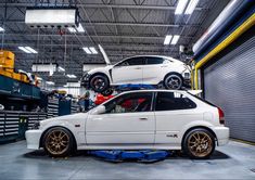 two cars are parked in a garage with one car on top of the other vehicle