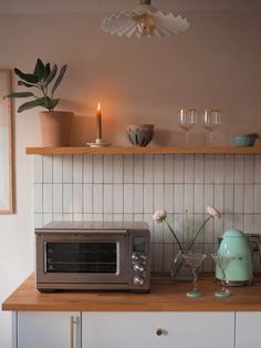 a kitchen counter with a toaster oven, microwave and vases on top of it