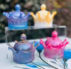 three little princess crowns sitting on top of a table next to each other and one is purple