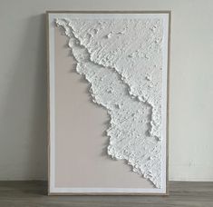 a large white paper cut in half on top of a wooden table next to a wall