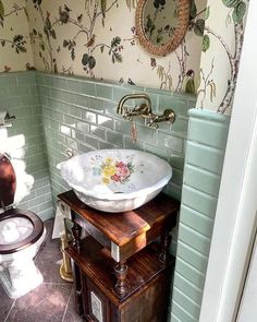 a bathroom with a sink and toilet next to a green wallpapered shower stall