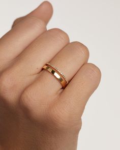 a woman's hand wearing a gold ring with two diamonds on the middle finger