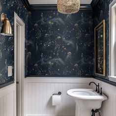 a bathroom decorated in blue and gold with an octopus theme on the wall, along with a white pedestal sink