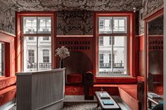 a living room with red walls and wooden furniture in front of two large windows that have ornate designs on them