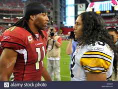 two football players on the sidelines talking to each other at a game - stock image