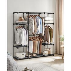 an open closet with clothes and shoes hanging on the rack, next to a bed