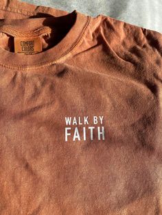 a brown shirt with the words walk by faith on it and a tag that says, comfort colors