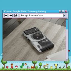 a cell phone sitting on top of a wooden table next to a game screen with an image of a camera