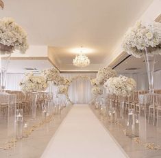 the aisle is lined with clear chairs and white flowers