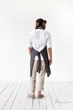 a man in white shirt and khaki pants standing on wooden floor with his back to the camera