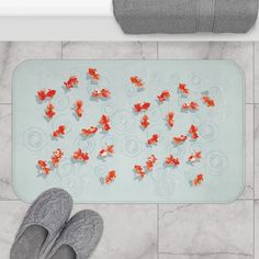 a pair of feet standing next to a bath mat with goldfish in water on it