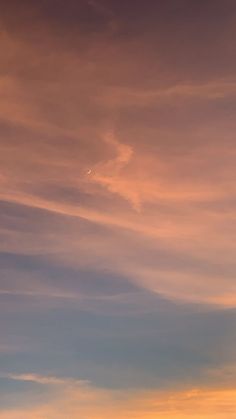 the airplane is flying high in the sky at sunset or dawn with an orange glow