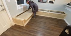 a woman is working on some furniture in a room with wood floors and white walls