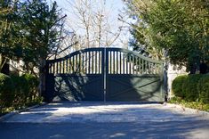 a gated driveway with trees and bushes surrounding it