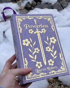 a person holding up a purple book in the snow