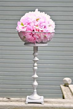 pink flowers are in a white vase on a stand