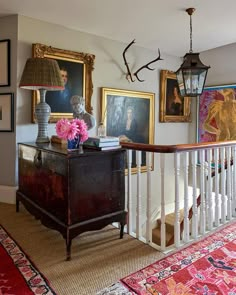 a living room filled with furniture and pictures on the wall next to a stair case