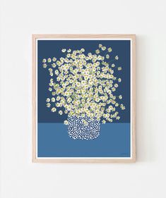 a blue and white print with daisies in a vase on the wall above it