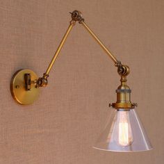 an antique brass wall light with a clear glass shade on the arm and one bulb