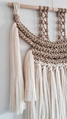 macrame wall hanging with tassels and wood stick on white wall background