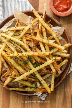 french fries with parmesan cheese and ketchup in a bowl on a wooden table