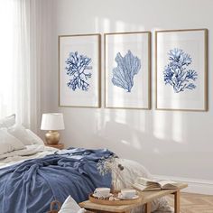 three blue and white seaweed prints hanging on the wall above a bed in a bedroom