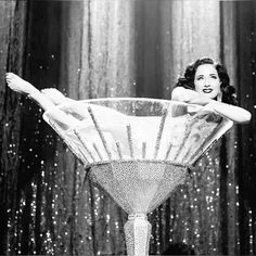 a woman sitting in a martini glass with her legs spread out to the side and arms outstretched