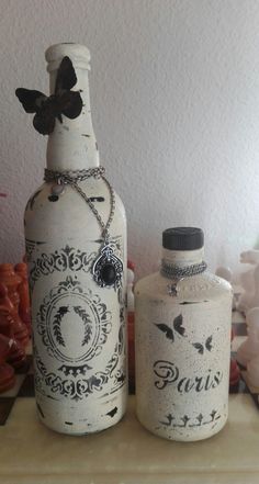 two white bottles sitting on top of a table next to each other and one has a butterfly on it