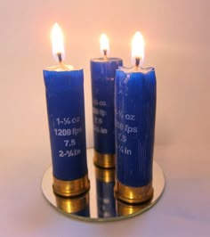 three blue candles sitting on top of a metal plate